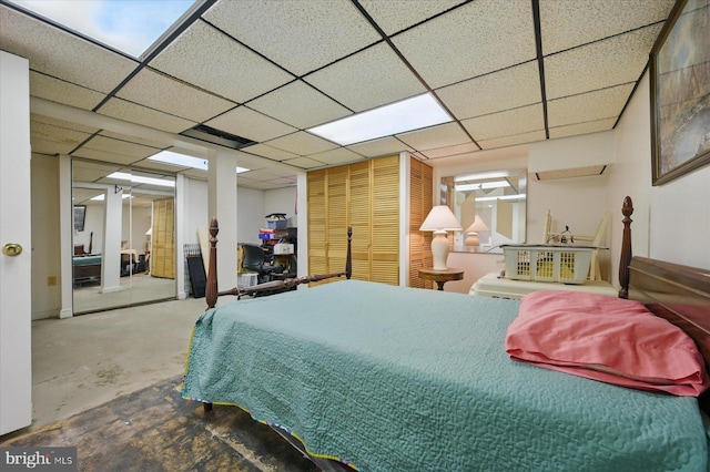 bedroom with concrete floors and a paneled ceiling