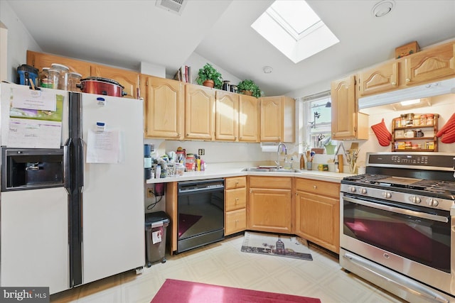 kitchen featuring stainless steel gas stove, white refrigerator with ice dispenser, dishwasher, a skylight, and a sink