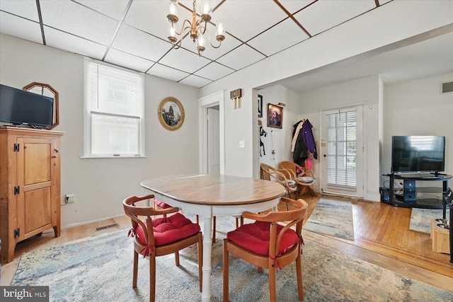 dining room with light wood-style floors, a chandelier, a drop ceiling, and baseboards