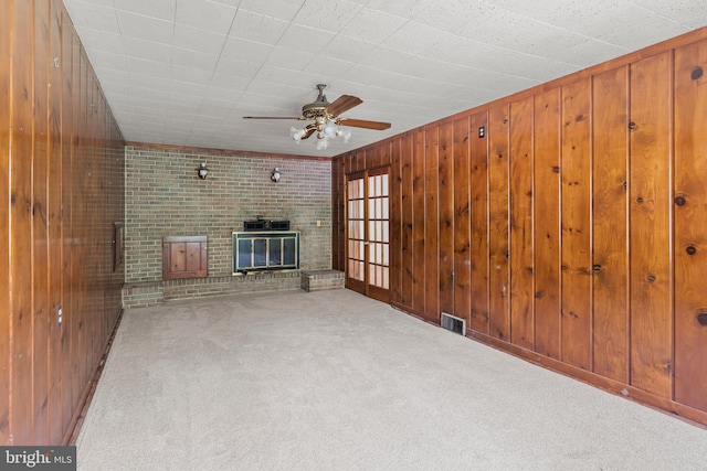 10699 Harding Rd, Laurel, MD 20723 - unfurnished living room with carpet flooring, a ceiling fan, wooden walls, and a brick fireplace