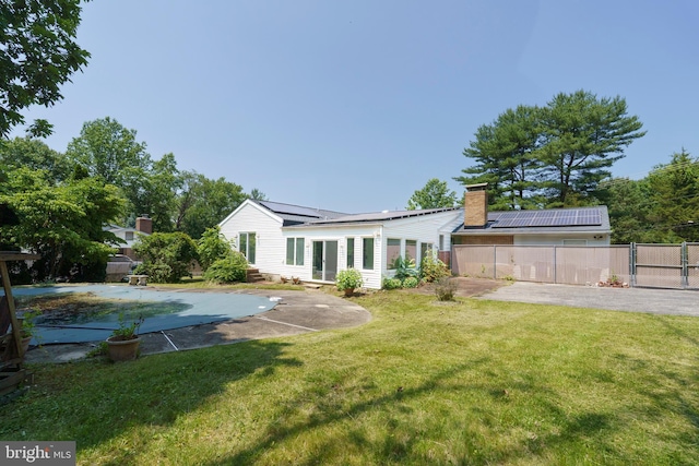 10699 Harding Rd, Laurel, MD 20723 - back of property featuring solar panels, a patio area, a gate, and a chimney