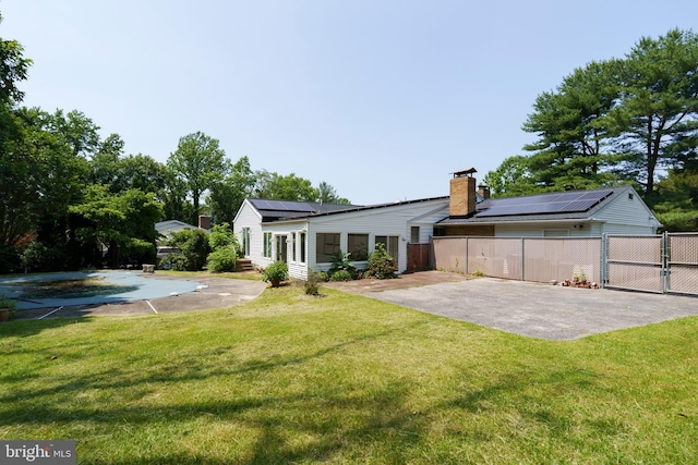 10699 Harding Rd, Laurel, MD 20723 - rear view of house featuring solar panels, a chimney, and a gate