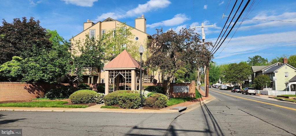 view of asphalt road with curbs, sidewalks, and street lights