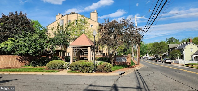 view of asphalt road with curbs, sidewalks, and street lights