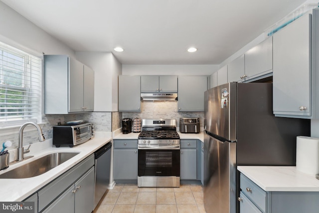 15609 Everglade Ln Unit F002, Bowie, MD 20716 - kitchen featuring appliances with stainless steel finishes, a sink, gray cabinetry, under cabinet range hood, and decorative backsplash