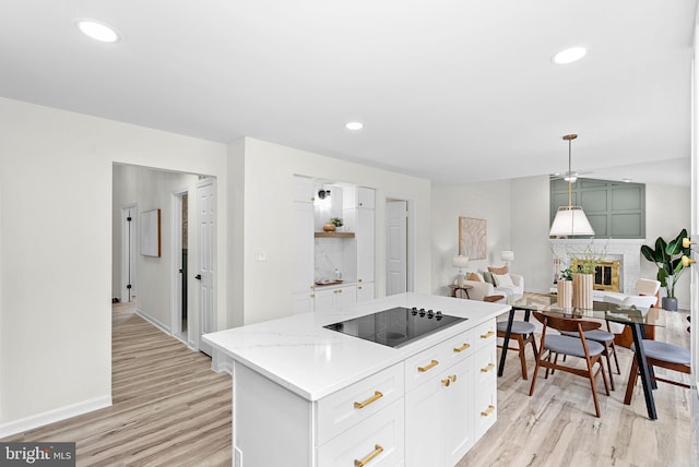 2619 Stone Mountain Ct, Herndon, VA 20170 - kitchen featuring black electric stovetop, light wood-type flooring, a fireplace, white cabinets, and a center island
