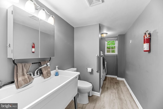 8328 Ridge View Rd, Lusby, MD 20657 - bathroom with washing machine and dryer, wood finished floors, toilet, baseboards, and vanity