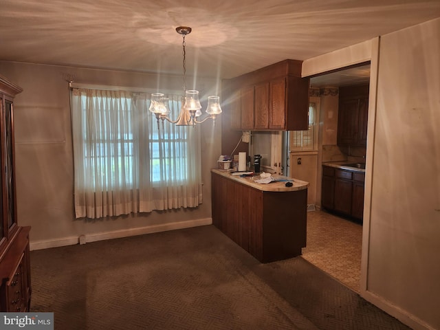 841 Highland Ave, Lancaster, PA 17603 - kitchen with a chandelier, light countertops, a peninsula, baseboards, and dark colored carpet