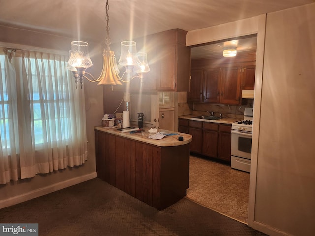 841 Highland Ave, Lancaster, PA 17603 - kitchen featuring white range with gas cooktop, light countertops, a peninsula, a sink, and a chandelier
