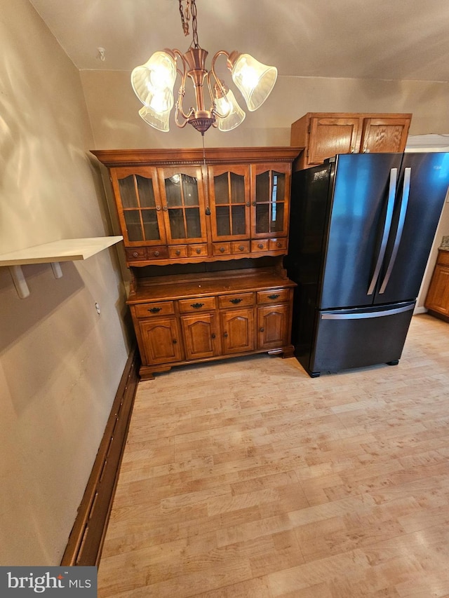 3 W Elm Ave, Baltimore, MD 21206 - kitchen with freestanding refrigerator, brown cabinetry, glass insert cabinets, light wood-style floors, and a chandelier