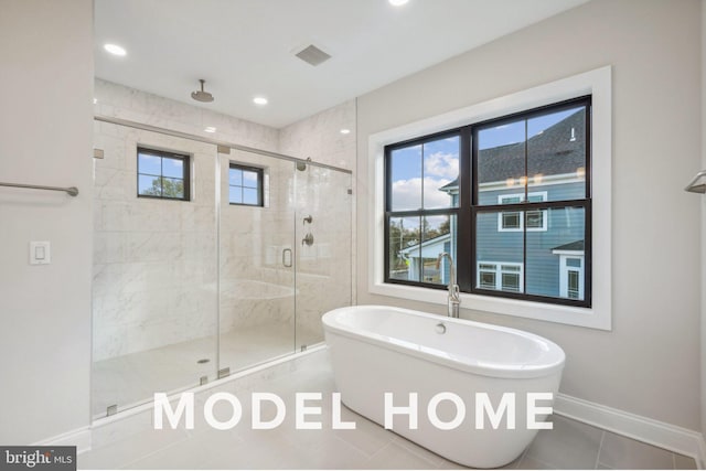 full bath featuring a stall shower, plenty of natural light, a soaking tub, and baseboards