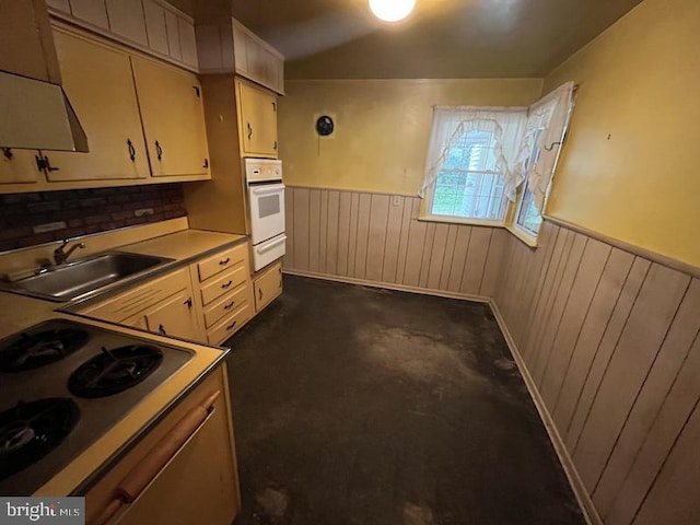 kitchen featuring a sink, white oven, wainscoting, a warming drawer, and cooktop