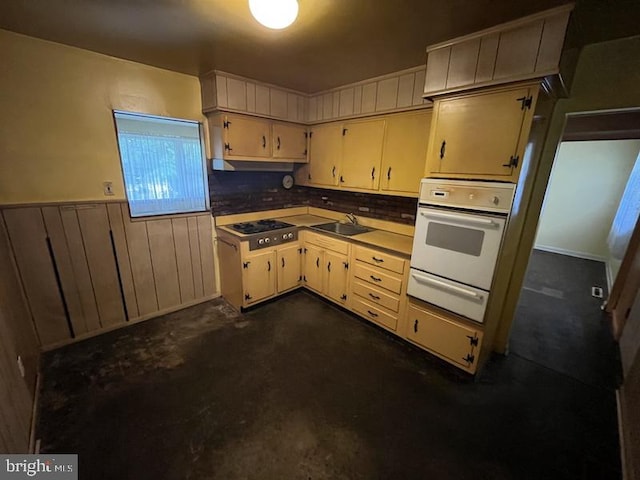 kitchen featuring oven, a warming drawer, a sink, stainless steel gas stovetop, and wainscoting