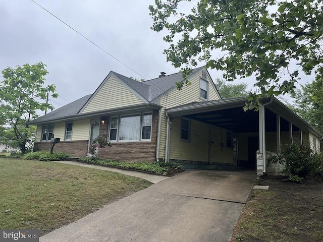 view of front of house with concrete driveway, an attached carport, and a front lawn