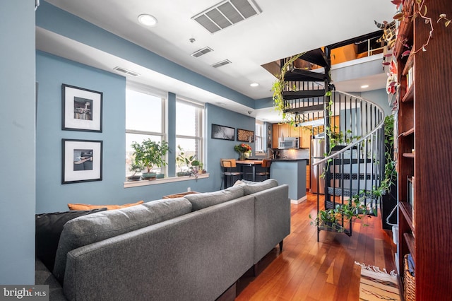 living area with light wood-style flooring, stairs, and recessed lighting