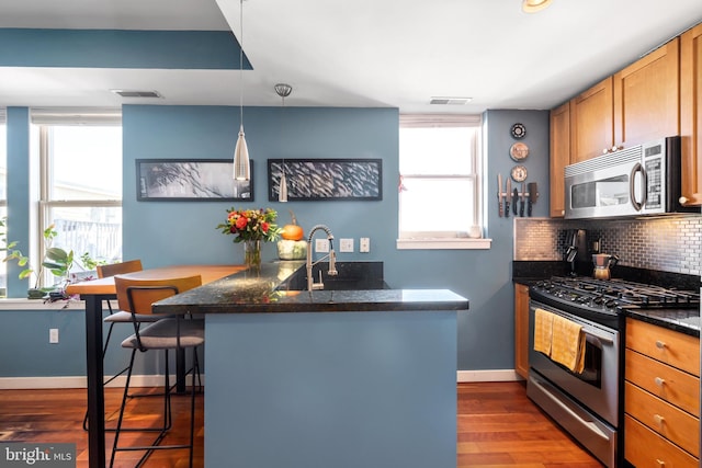 kitchen featuring stainless steel appliances, plenty of natural light, backsplash, and a breakfast bar area