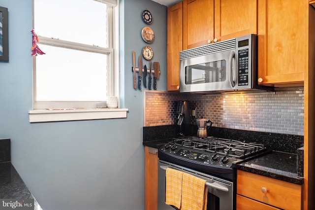 kitchen with stainless steel appliances, tasteful backsplash, plenty of natural light, and dark stone counters