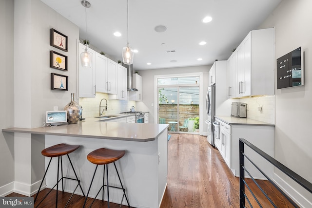 721 S Smedley St, Philadelphia, PA 19146 - kitchen with a sink, stainless steel appliances, a kitchen bar, wood finished floors, and recessed lighting