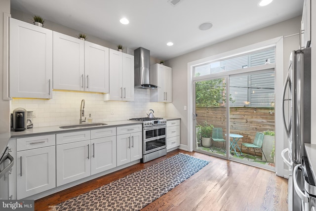 721 S Smedley St, Philadelphia, PA 19146 - kitchen featuring appliances with stainless steel finishes, wall chimney exhaust hood, a sink, backsplash, and wood finished floors
