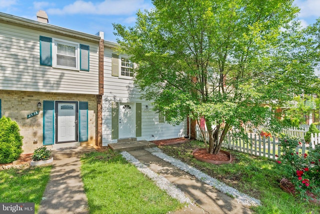 multi unit property with fence, brick siding, and a chimney