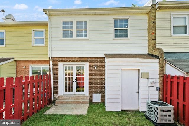 rear view of property featuring french doors, central AC unit, brick siding, and a fenced backyard