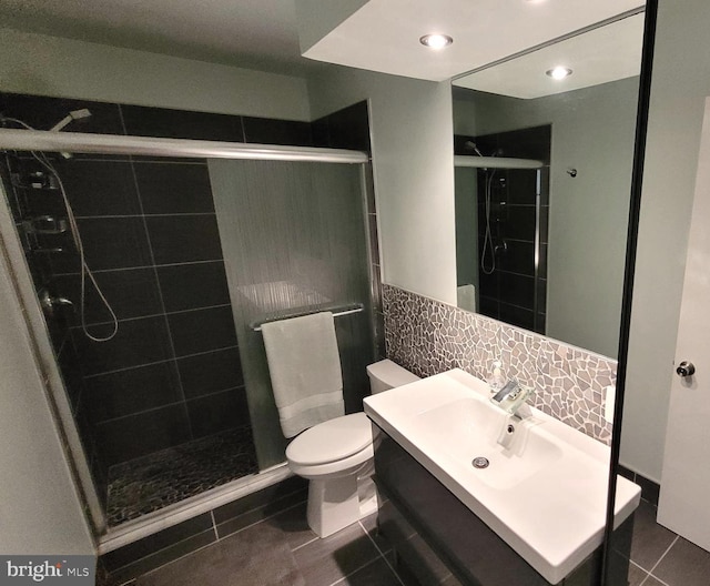 full bath with a shower stall, tile patterned floors, toilet, vanity, and tile walls