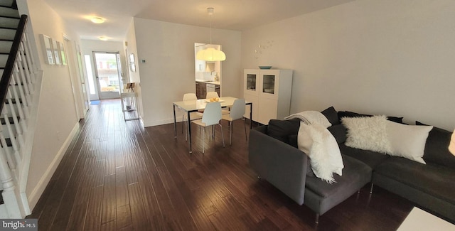 living room with stairway, dark wood-type flooring, and baseboards