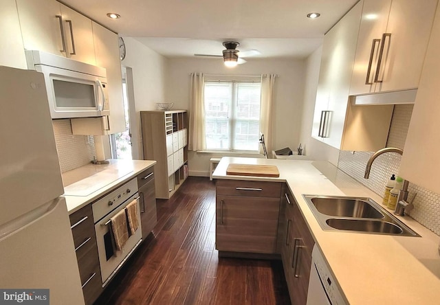 kitchen with white appliances, a sink, light countertops, backsplash, and ceiling fan