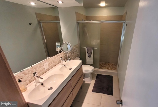 bathroom featuring a stall shower, tile patterned floors, double vanity, and toilet