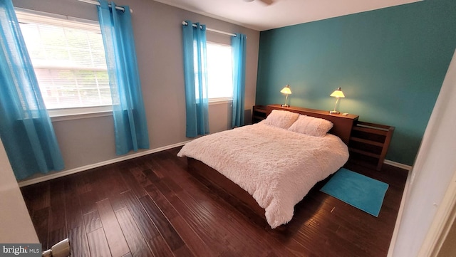 bedroom with dark wood-type flooring and baseboards