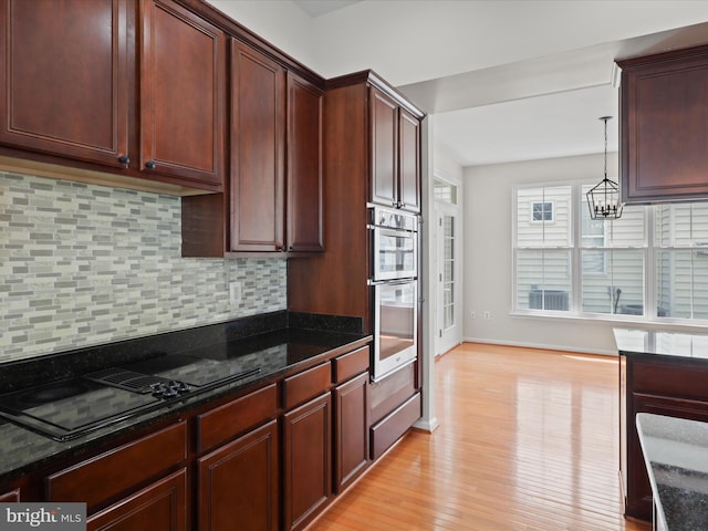 17494 Lethridge Cir, Round Hill, VA 20141 - kitchen featuring tasteful backsplash, stainless steel double oven, dark stone counters, light wood-type flooring, and a chandelier