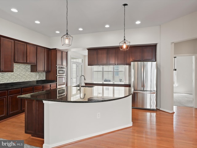 17494 Lethridge Cir, Round Hill, VA 20141 - kitchen featuring appliances with stainless steel finishes, a kitchen island with sink, backsplash, pendant lighting, and light wood finished floors