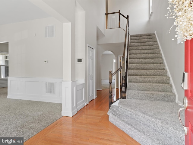 17494 Lethridge Cir, Round Hill, VA 20141 - stairs featuring arched walkways, wainscoting, wood finished floors, and a high ceiling
