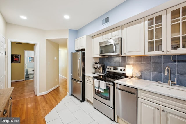 1725 Willard St NW Unit 3, Washington, DC 20009 - kitchen with stainless steel appliances, glass insert cabinets, tasteful backsplash, recessed lighting, and white cabinetry