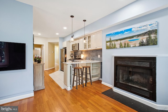 1725 Willard St NW Unit 3, Washington, DC 20009 - kitchen with appliances with stainless steel finishes, a breakfast bar area, glass insert cabinets, light countertops, and a peninsula