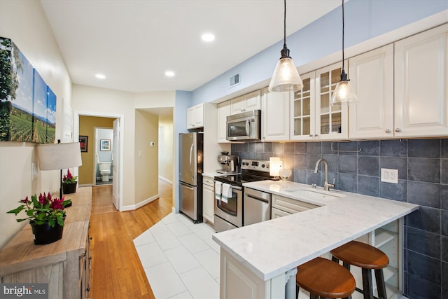 1725 Willard St NW Unit 3, Washington, DC 20009 - kitchen featuring appliances with stainless steel finishes, light stone countertops, glass insert cabinets, hanging light fixtures, and recessed lighting
