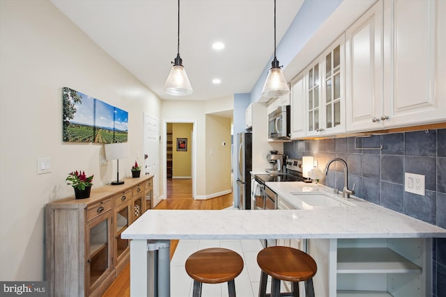 1725 Willard St NW Unit 3, Washington, DC 20009 - kitchen with stainless steel appliances, a breakfast bar, light stone countertops, light wood-type flooring, and tasteful backsplash