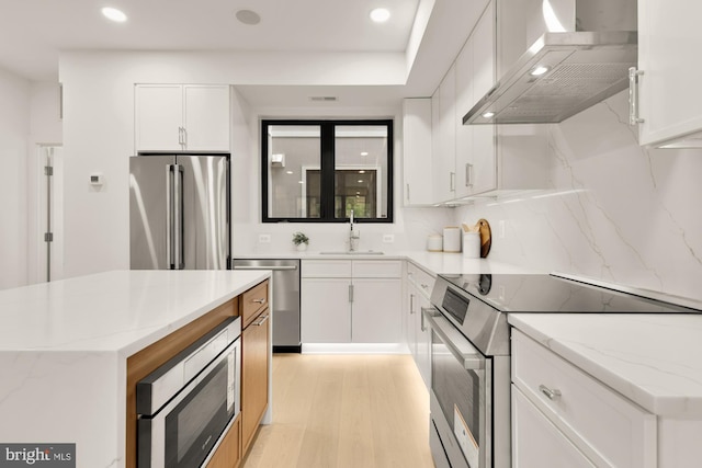 503 L St NE Unit B, Washington, DC 20002 - kitchen with appliances with stainless steel finishes, wall chimney exhaust hood, a sink, light wood finished floors, and white cabinetry