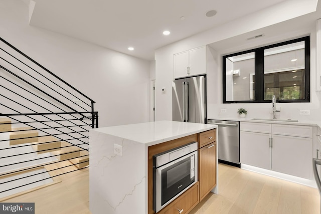 503 L St NE Unit B, Washington, DC 20002 - kitchen featuring appliances with stainless steel finishes, a sink, light wood-style flooring, white cabinetry, and recessed lighting