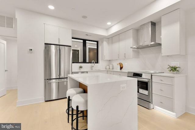503 L St NE Unit B, Washington, DC 20002 - kitchen featuring stainless steel appliances, wall chimney range hood, light wood-style flooring, a breakfast bar area, and recessed lighting