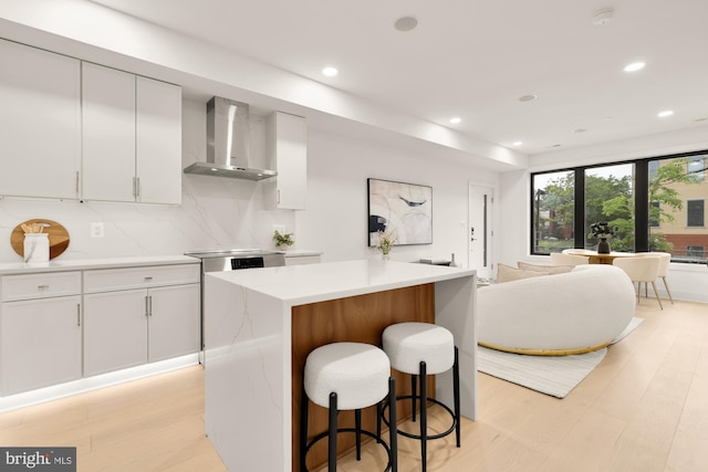 503 L St NE Unit B, Washington, DC 20002 - kitchen with wall chimney range hood, light wood-style flooring, a breakfast bar, light countertops, and recessed lighting