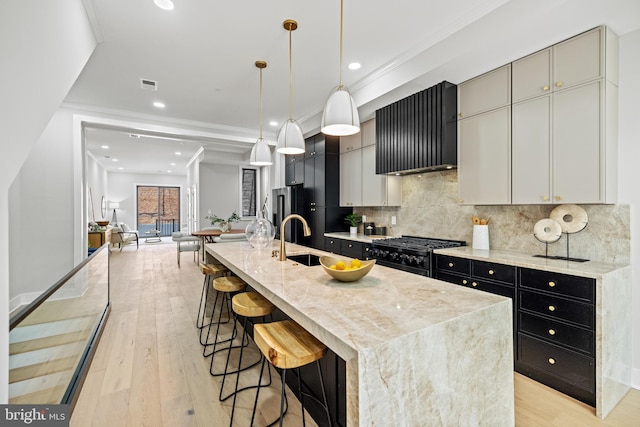 1407 1st St NW Unit 1, Washington, DC 20001 - kitchen with wall chimney range hood, black appliances, light wood-style flooring, dark cabinetry, and decorative backsplash