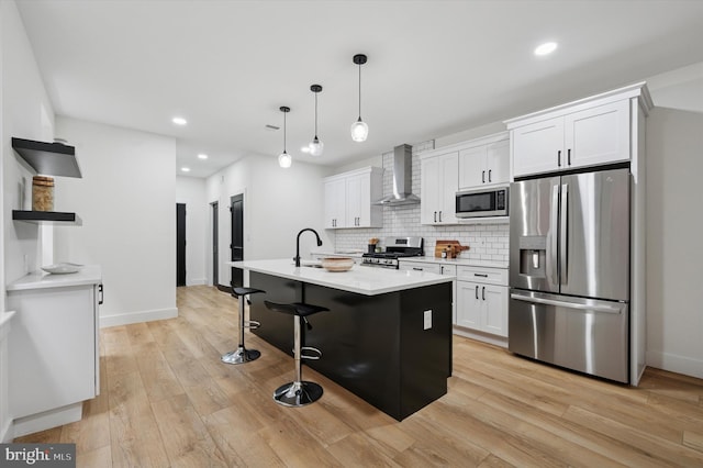 642 S 51st St, Philadelphia, PA 19143 - kitchen featuring appliances with stainless steel finishes, wall chimney exhaust hood, white cabinetry, light wood-style flooring, and recessed lighting