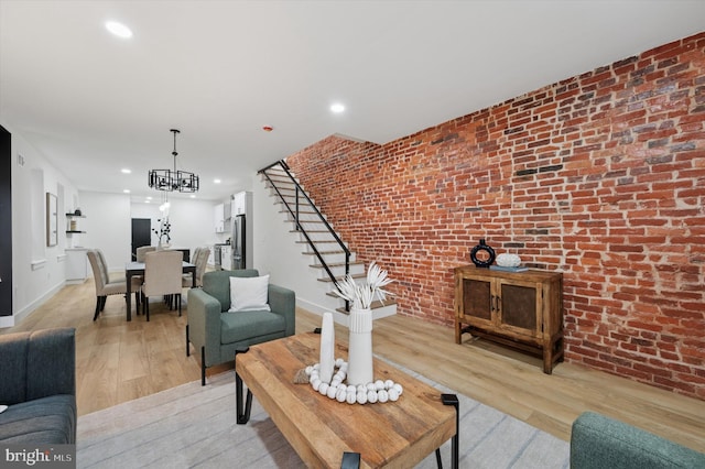 642 S 51st St, Philadelphia, PA 19143 - living area featuring brick wall, a chandelier, light wood finished floors, stairs, and baseboards
