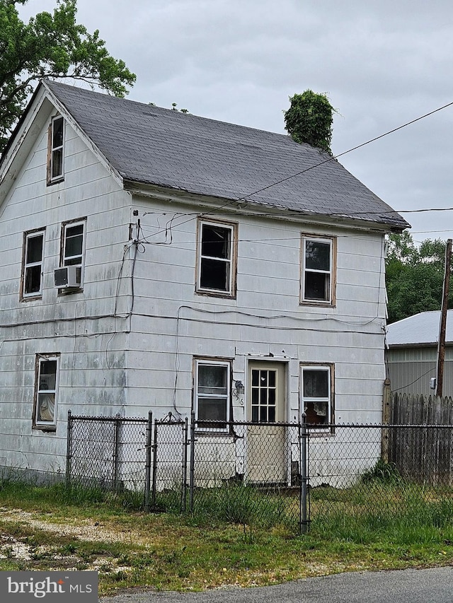 back of property with a fenced front yard, roof with shingles, and cooling unit