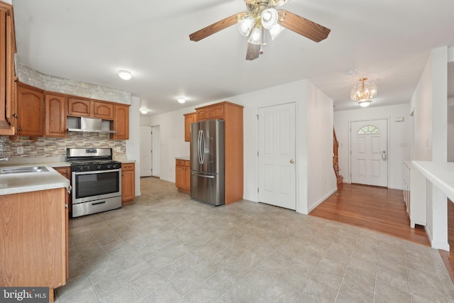 kitchen featuring appliances with stainless steel finishes, extractor fan, light countertops, a chandelier, and a sink