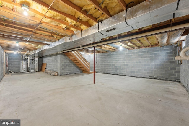 unfinished below grade area featuring water heater, stairway, and heating unit