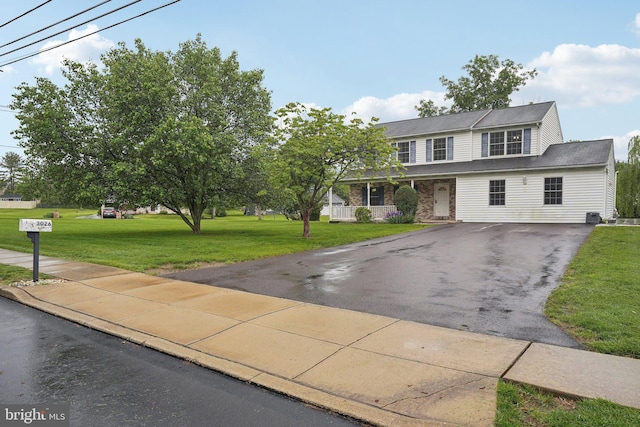 view of front of home with asphalt driveway, a front yard, and a porch
