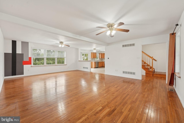 unfurnished living room with stairway, light wood finished floors, ceiling fan, and baseboards