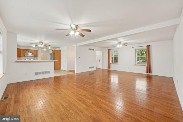 unfurnished living room featuring ceiling fan, light wood-style flooring, and baseboards